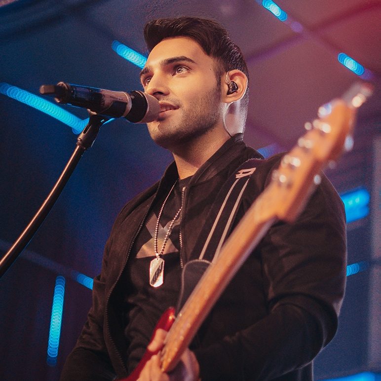 Singer Behram Siganporia holds a guitar in his hand and sings into a microphone