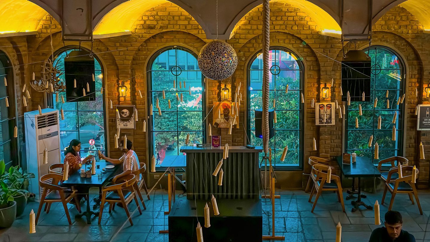 Interior view of Watson’s brewery pub, where people sit at tables in front of high windows