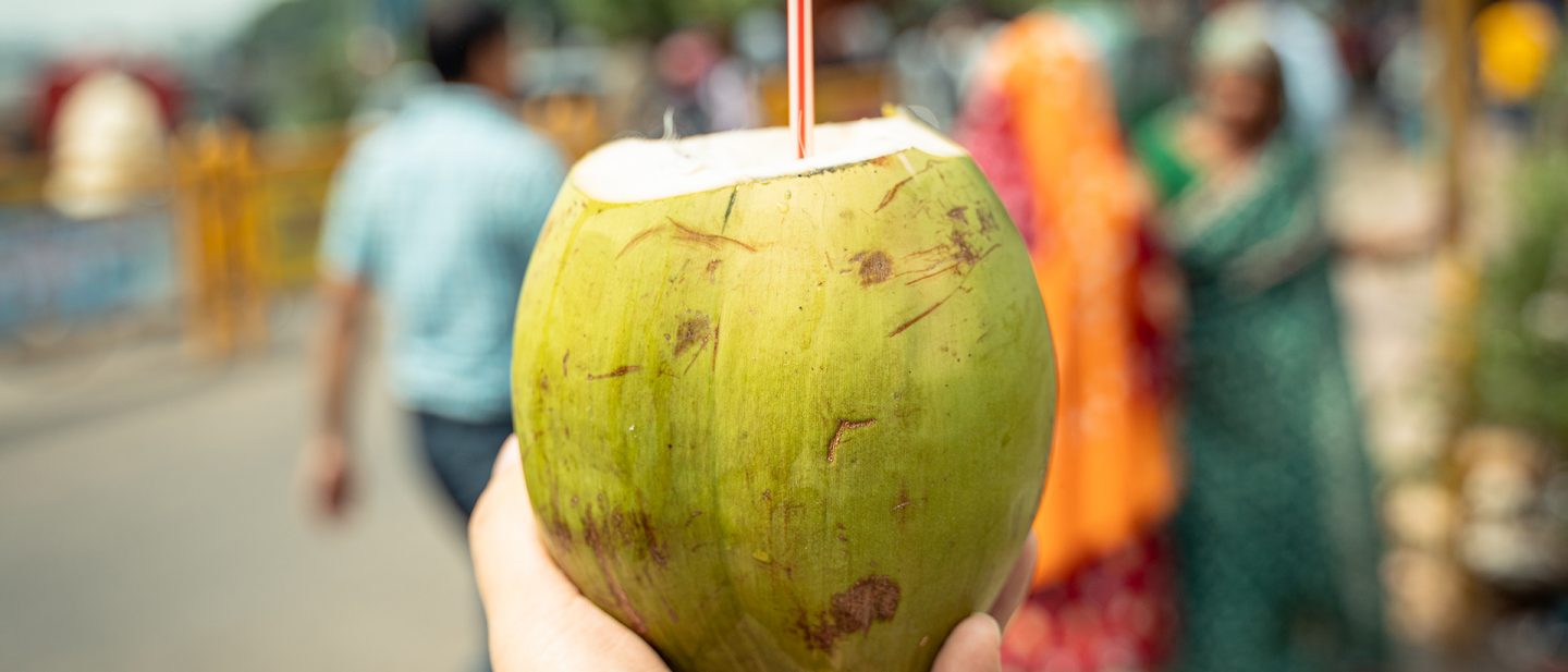 Close-up of a cracked coconut with a straw stuck in it