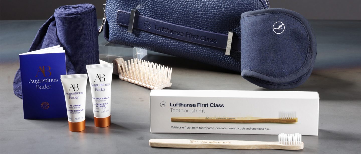Contents of the amenity kits in Lufthansa First Class: creams created by Professor Dr. Augustinus Bader, a toothbrush and a hairbrush; in the background a dark blue cosmetic bag and a sleep mask.