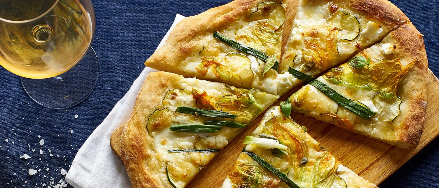 Vegetarian pizza with zucchini flowers, onion, courgette and cheese.