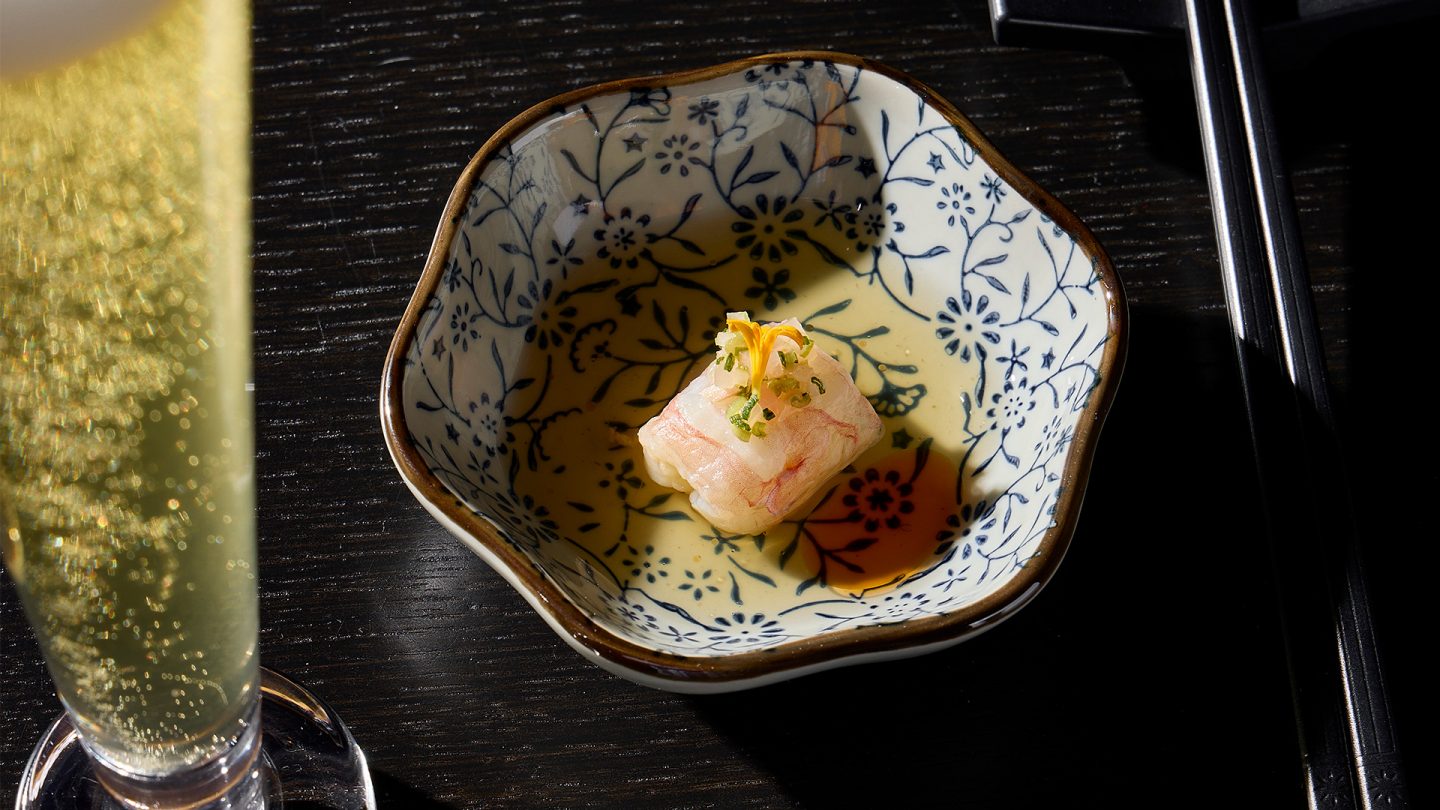 Nobly served fish sushi with a glass of beer next to it and chopsticks.