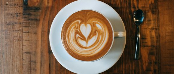 A cup of flat white on a wooden café table