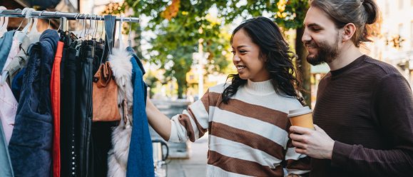 A millennial couple is taking a look at a second-hand clothing store