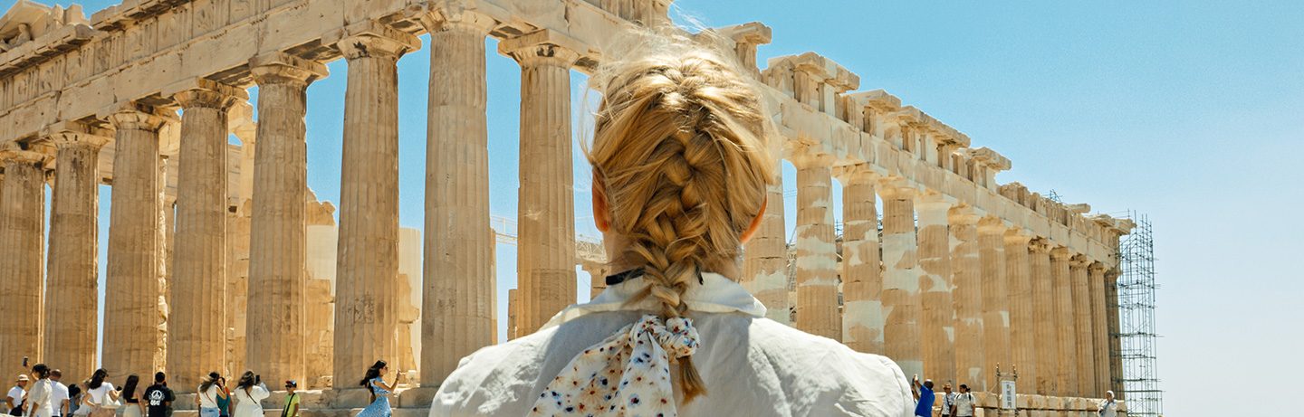 Women with braided hair stands in front of the Parthenon Temple on the Acropolis in Athens