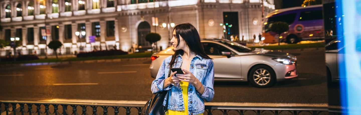 A young woman in a denim jacket stands at a crossroads in Madrid.
