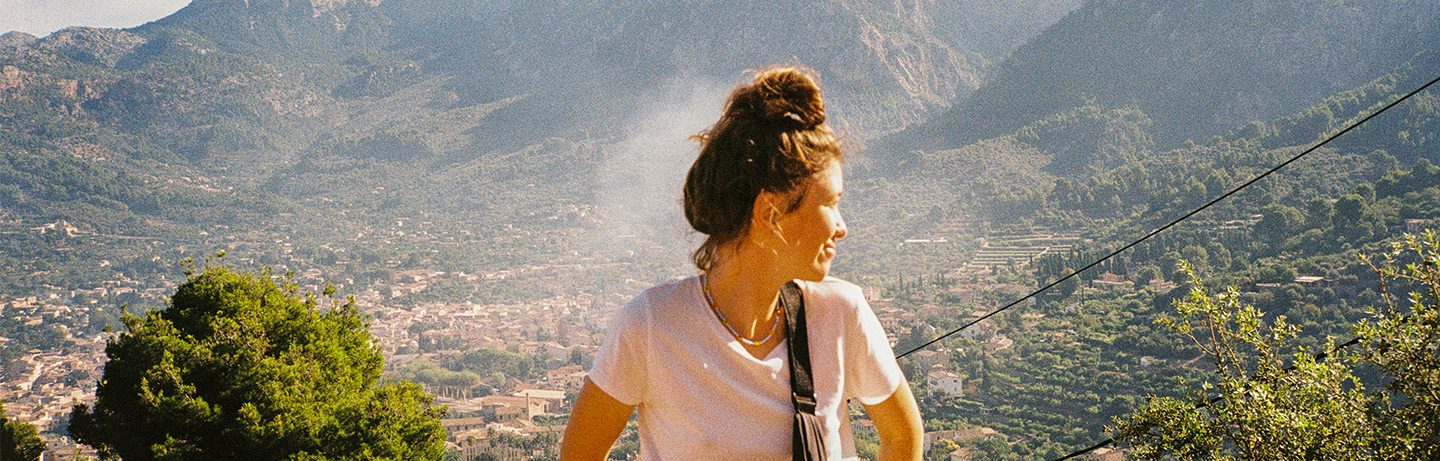  Woman, turns sideways out of the picture, in the background you can see a typical mallorquin mountain village