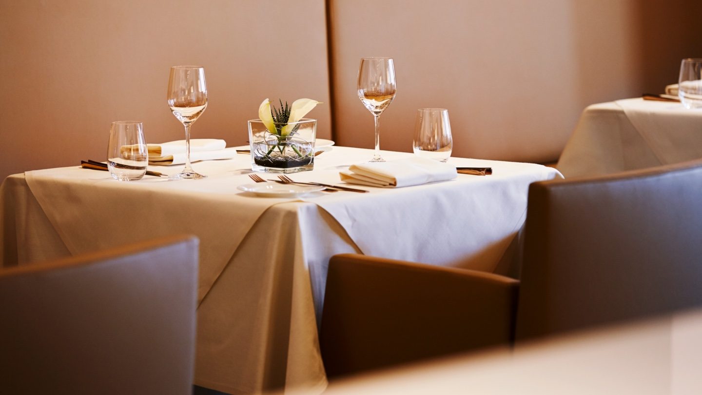 Elegant dining table with white linens, crystal glasses, and a floral centerpiece.