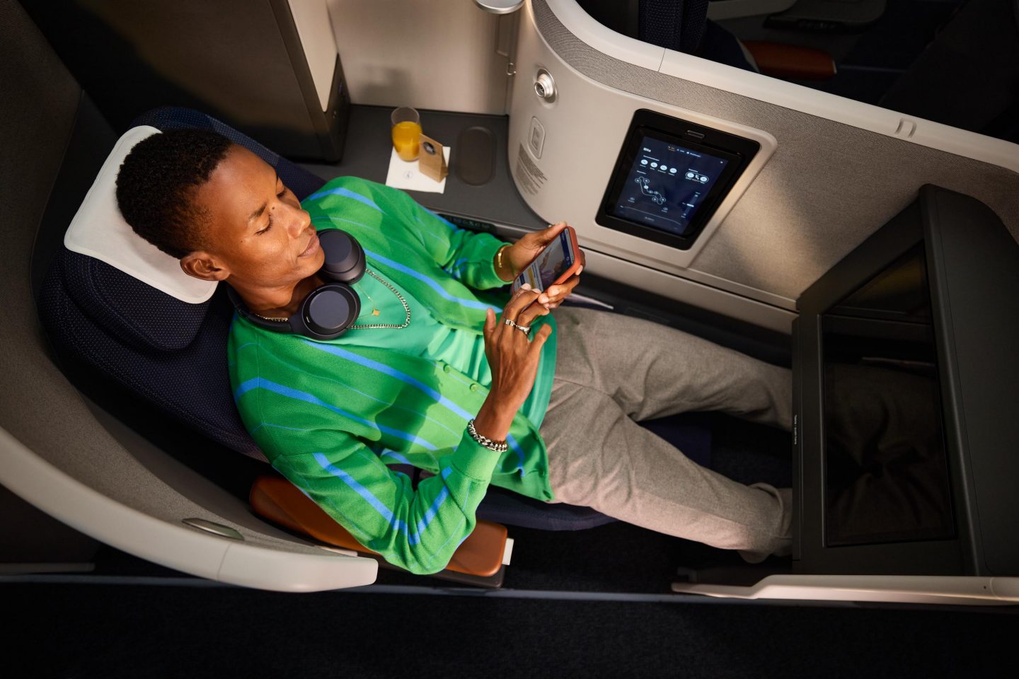 Mann mit Kopfh&ouml;rern sitzt im Extra Long Bed der Business Class. // Man with headphones is sitting in the extra long bed seat in business class. 