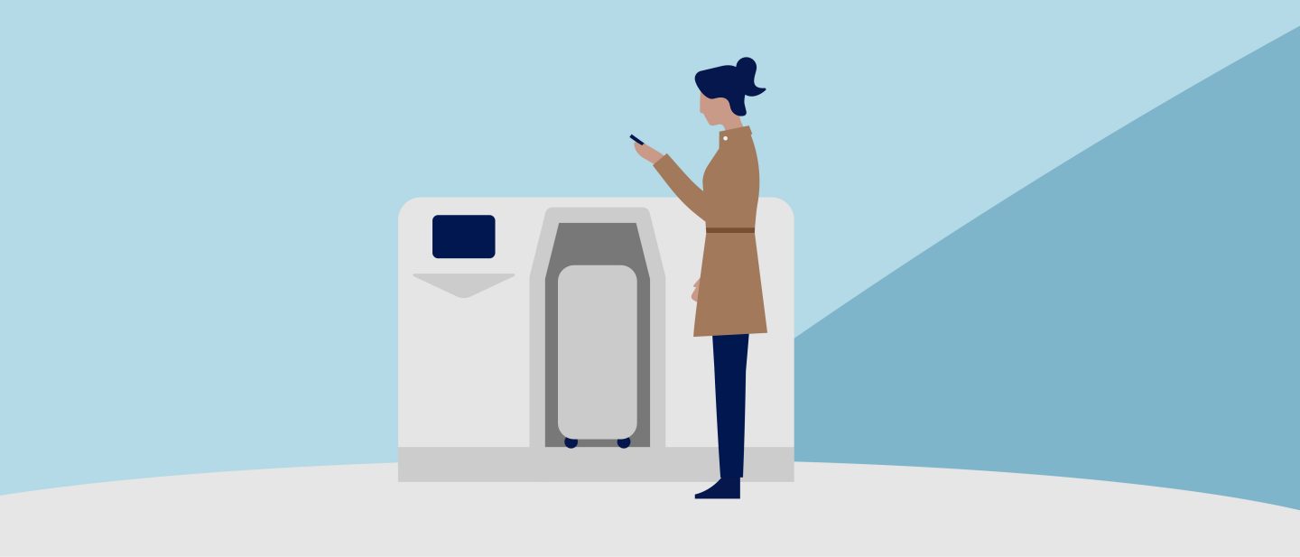 Traveler scanning a smartphone at a self-service baggage drop kiosk.