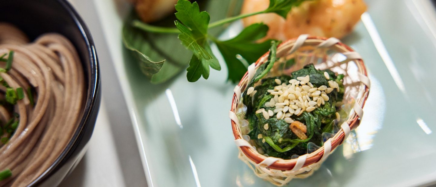 Basket with sesame spinach, soba noodles, and herbs.