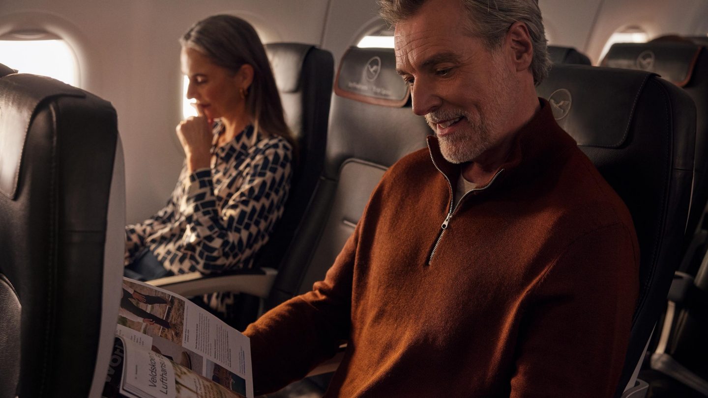 Two passengers reading next to each other in Lufthansa Business Class.