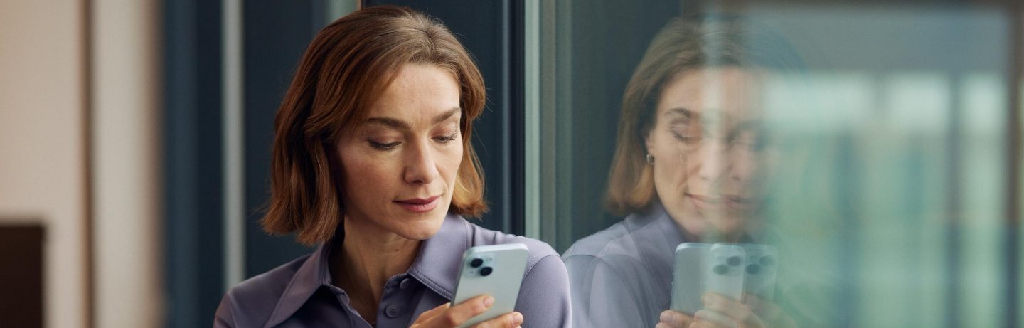 Eine Frau steht in der Lounge am Fenster und telefoniert. // A woman is standing by the window in the lounge talking on the phone.
