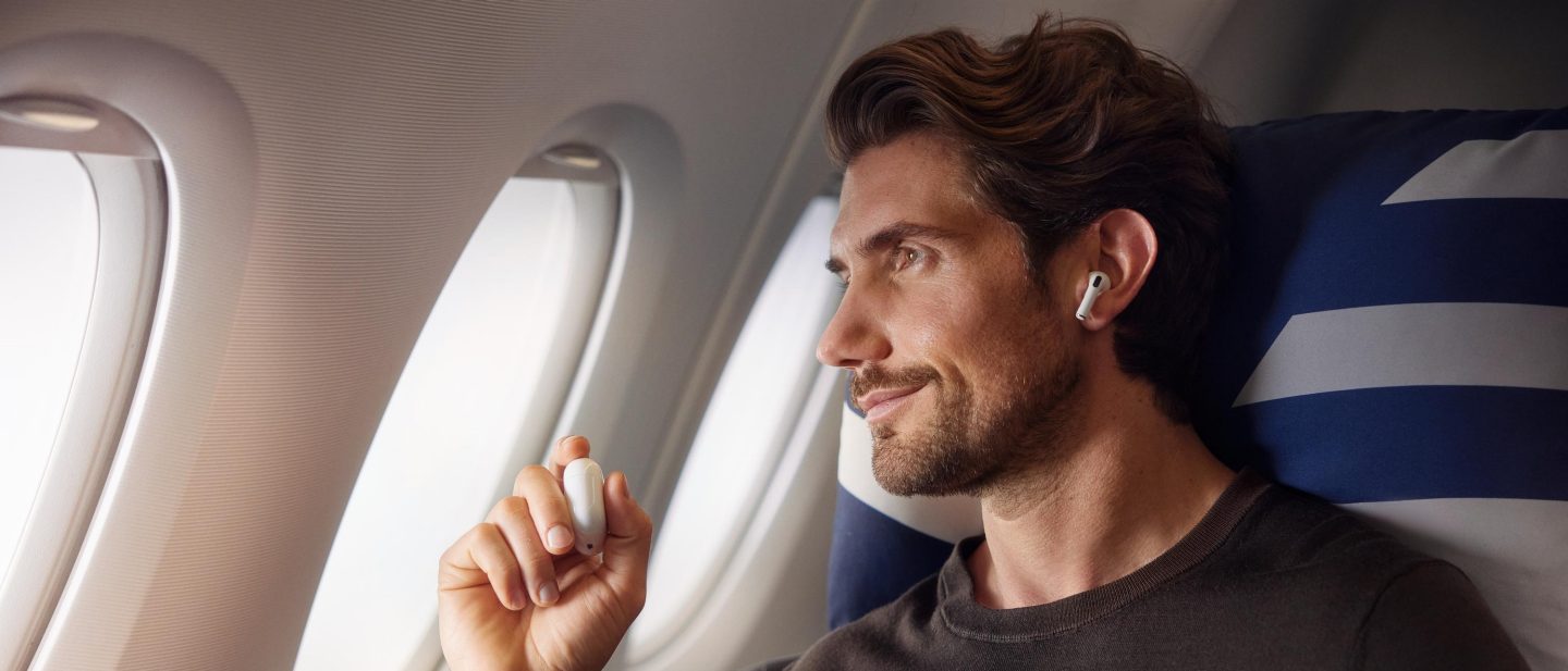 Ein Mann genie&szlig;t den Flug in der Business Class,  schaut aus dem Fenster und h&ouml;rt dabei Musik. // A man is enjoying the flight in Business Class, looking out of the window and listening to music.