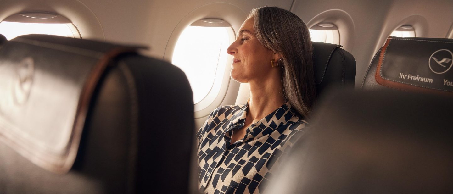 Eine Frau sitzt in der Business Class der A320neo und schaut entspannt aus dem Fenster. // A woman sits in Business Class on the A320neo and looks out of the window, relaxed.