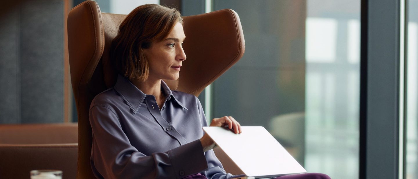 A woman sits in an armchair, gazing out the window.