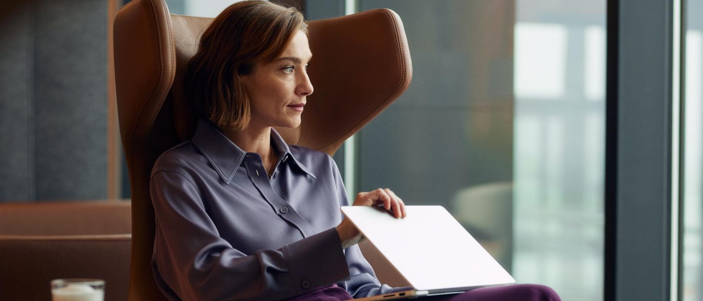 A woman sits in an armchair, gazing out the window.