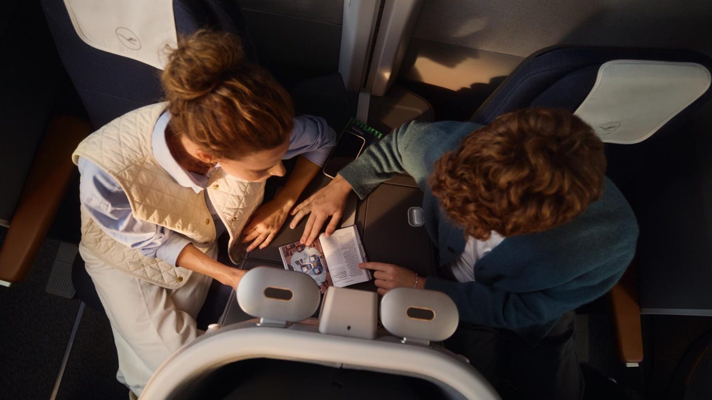 Overhead view of two passengers in first class reading a magazine together.