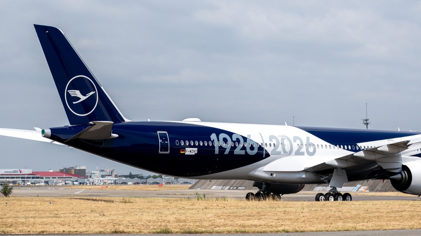 Lufthansa aircraft tail showing the crane logo and 1926-2026 anniversary livery at the airport.