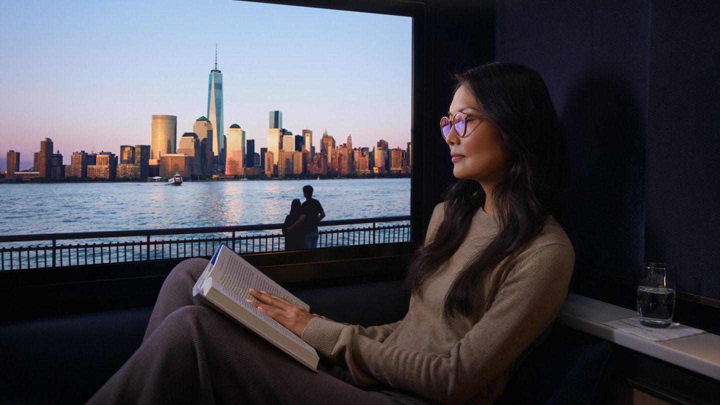 Relaxing traveler reads a book with a stunning New York City skyline view at sunset.