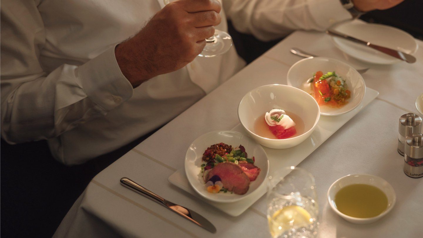 A man dining at a table set with wine glasses, savoring a modern tasting menu in a fine dining setting.