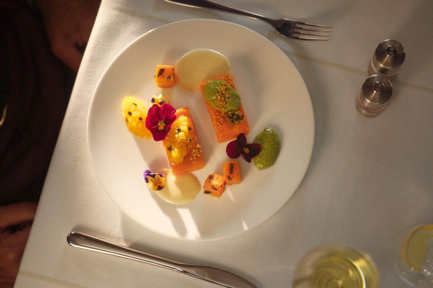 A white plate featuring an artfully arranged modern fine dining tasting menu.
