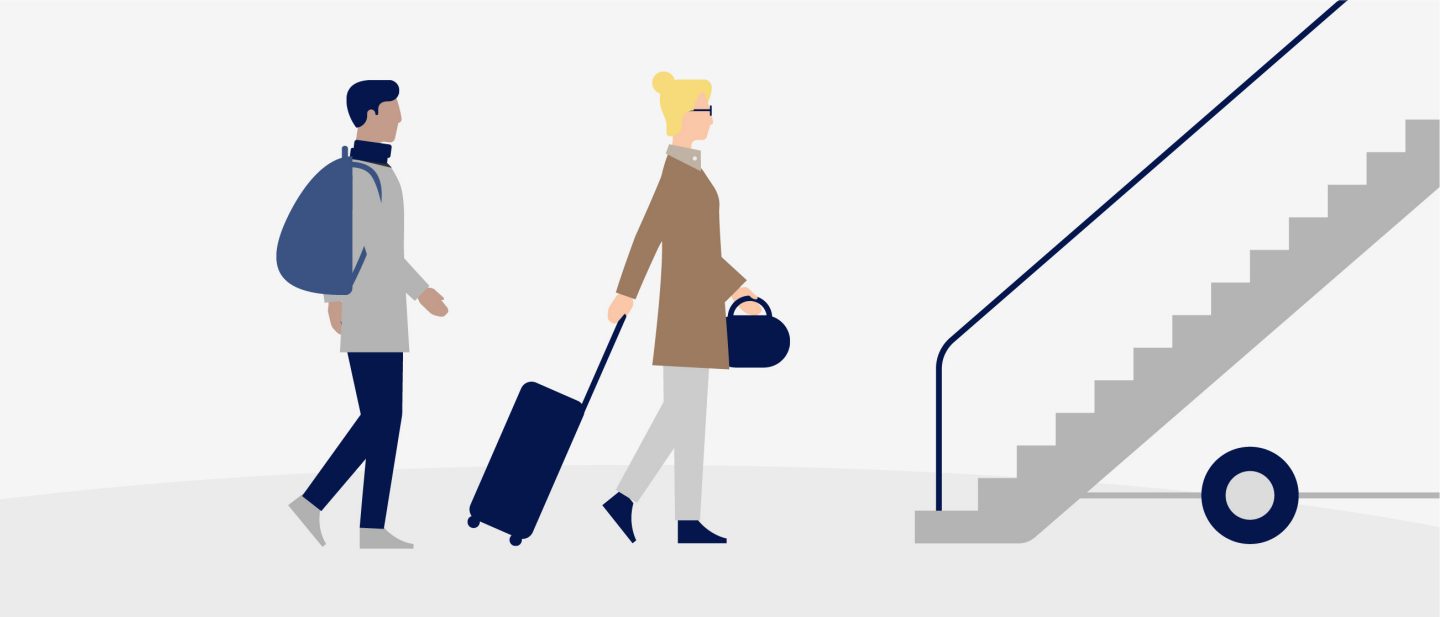 Two travelers walking with carry-on luggage near an escalator.