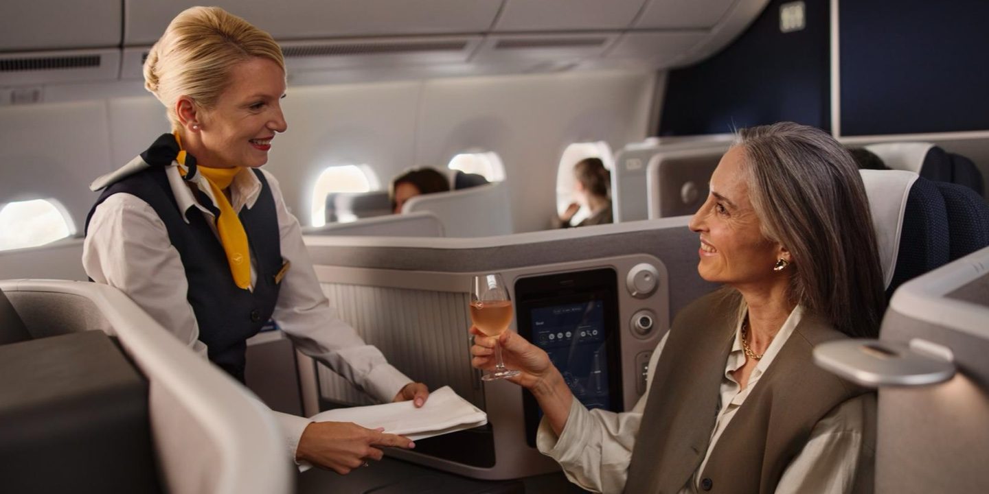 Would you like anything else? A female flight attendant hands a female passenger a drink.