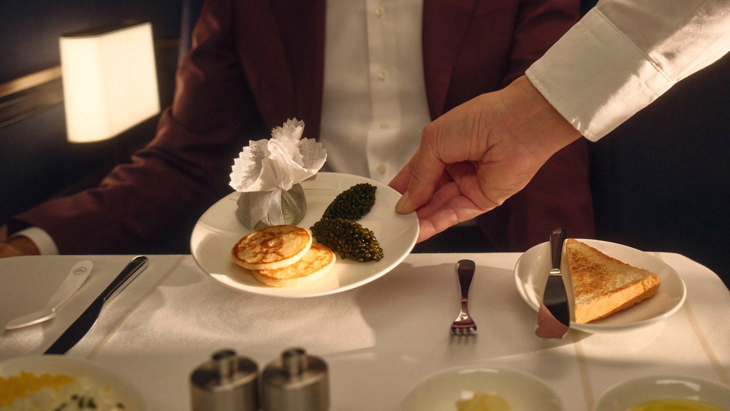 Waiter serving caviar and blinis in an elegant, dimly lit setting.