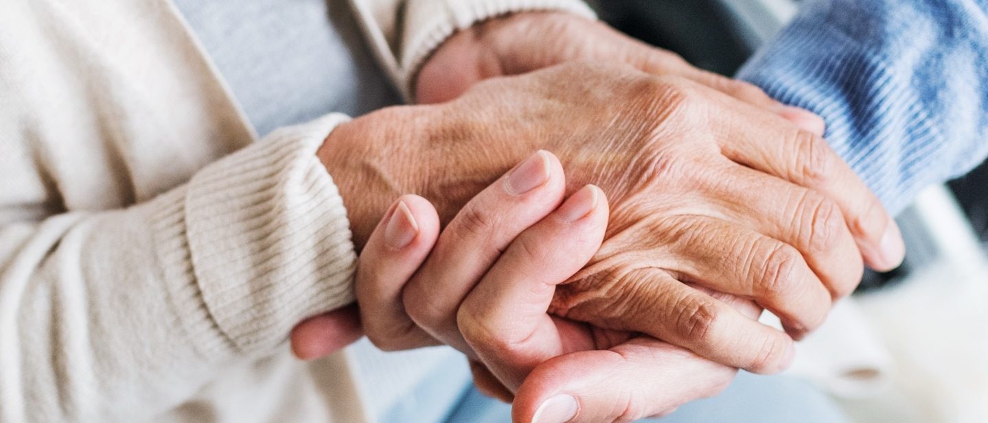 Two people hold each other’s hands in a supportive way.