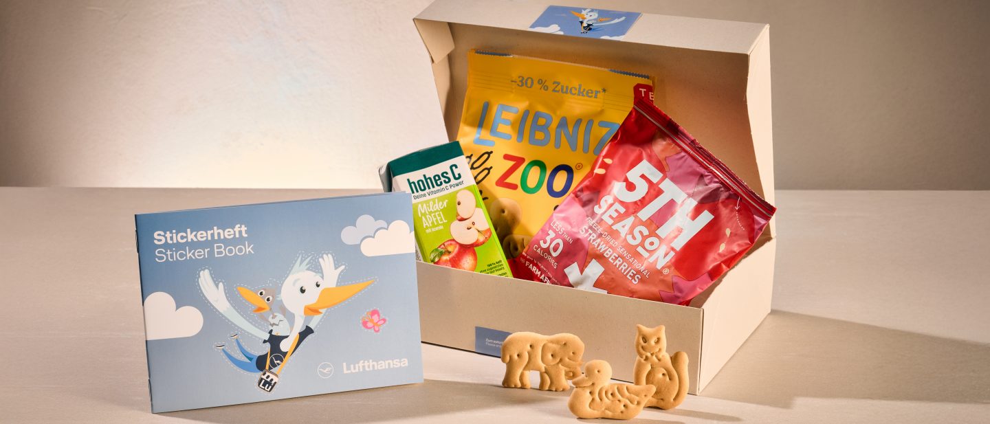 Snack box with cookies, dried strawberries, apple juice, and a sticker book.