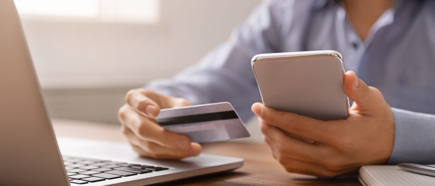 Closeup of unrecognizable businessman paying his bills online using application in smartphone and credit card, crop