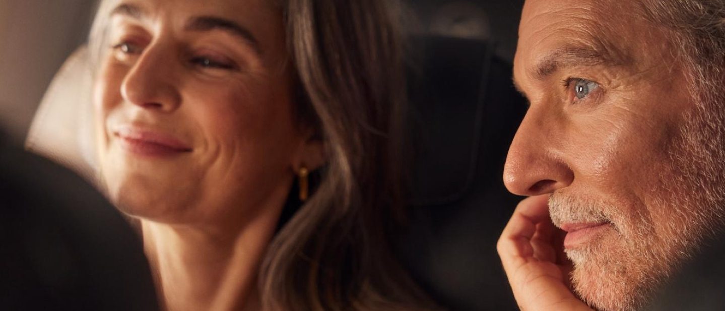 A couple sit together in a plane looking happy and relaxed.
