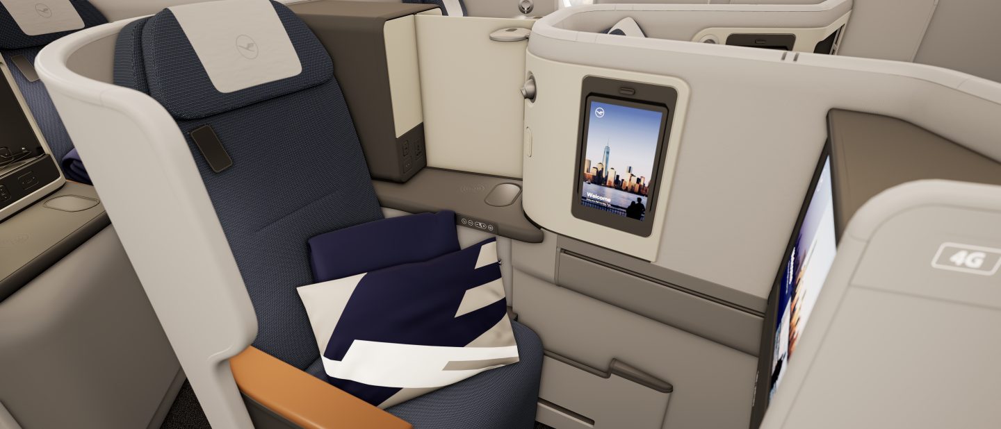 Spacious Lufthansa business class seat with personal screen & amenities.
