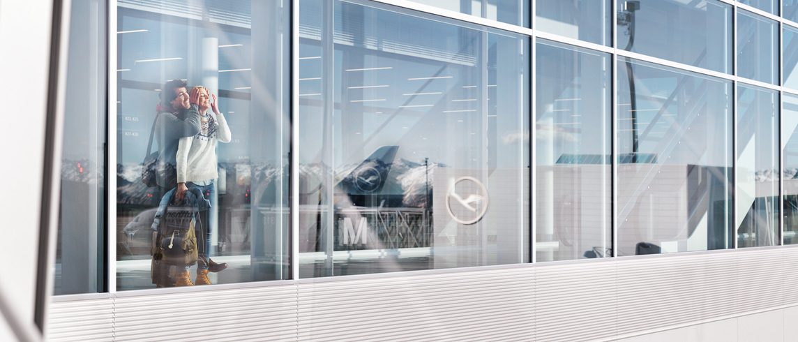 Couple look out of a window front at Munich Airport 