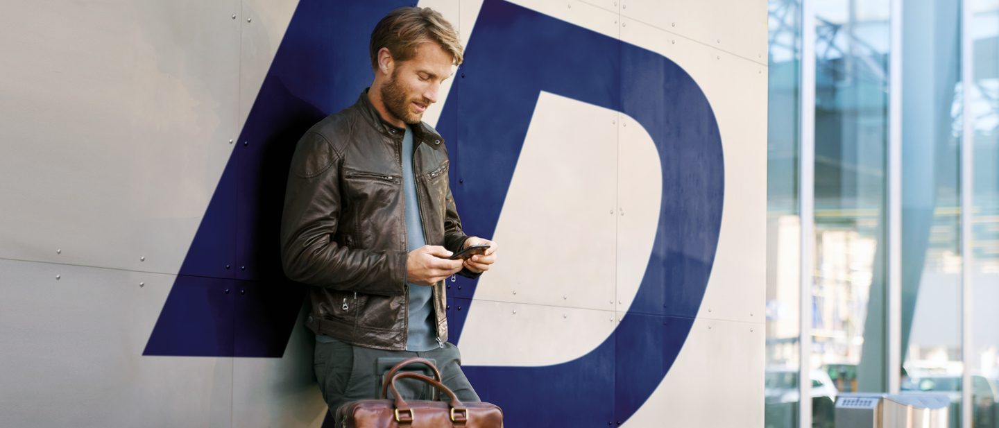 Young man with smartphone in his hand. He is logging into his account using his Travel ID/email address.