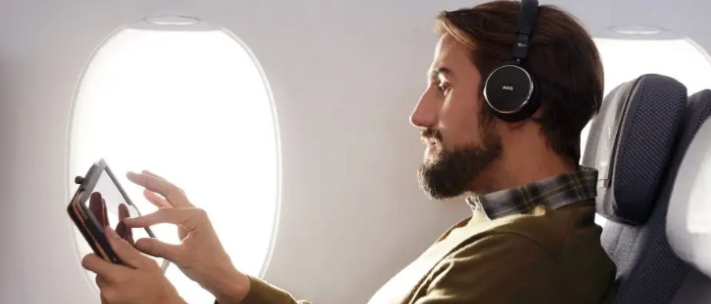 Young man with smartphone in his hand. He is using the internet on board the aircraft to listen to music online.