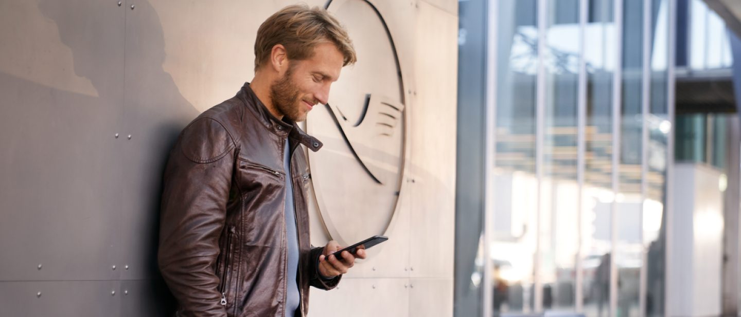 Young man with smartphone in his hand. He is logging into his account using his Travel ID/email address.