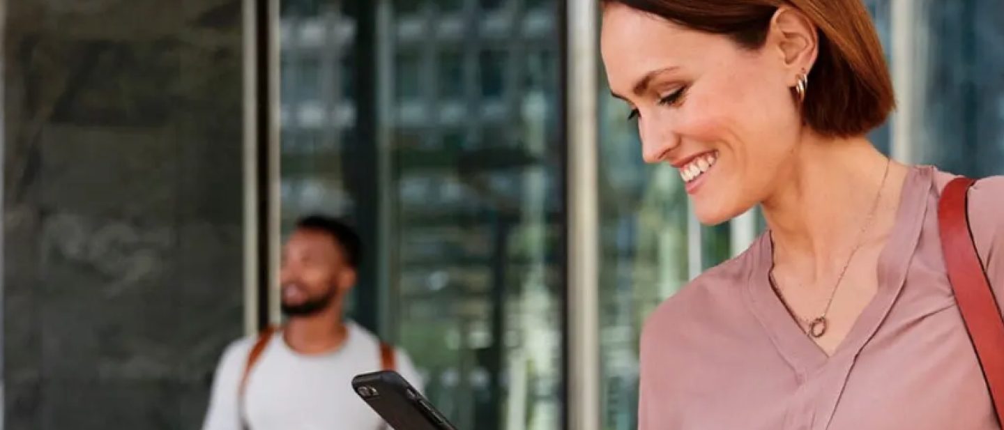 Young woman with smartphone in her hand. She is using the Lufthansa app to view information about her trip.
