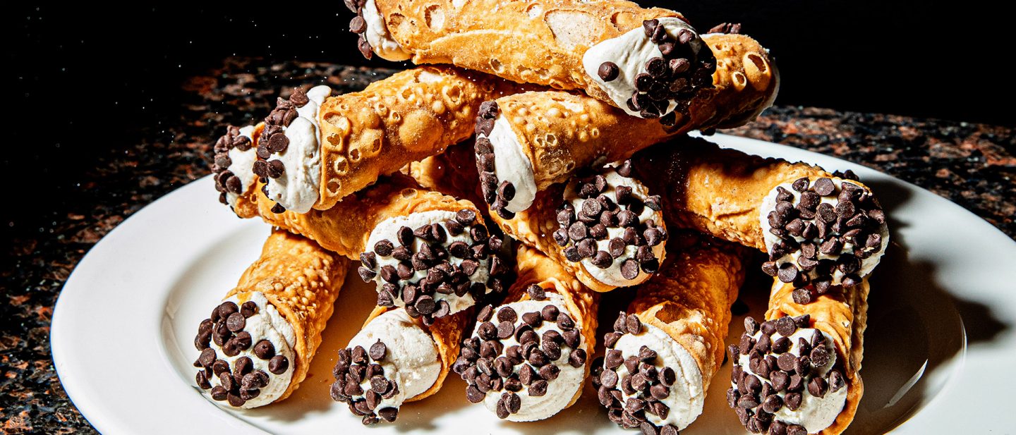 A stack of cannoli filled with ricotta and chocolate chips on a white plate