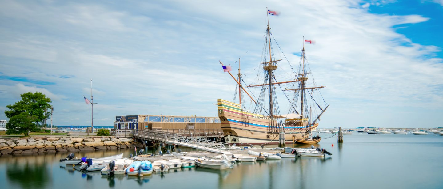 The Mayflower II docked in Plymouth Harbor under a partly cloudy sky