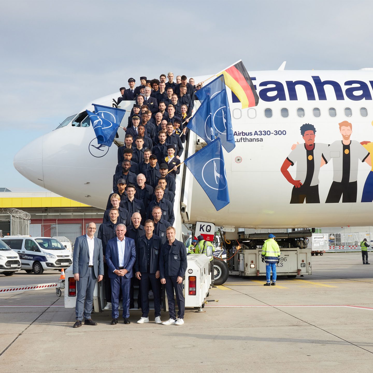 The German national team stands on the steps of a Lufthansa Airbus A330. They are holding flags in their hands.