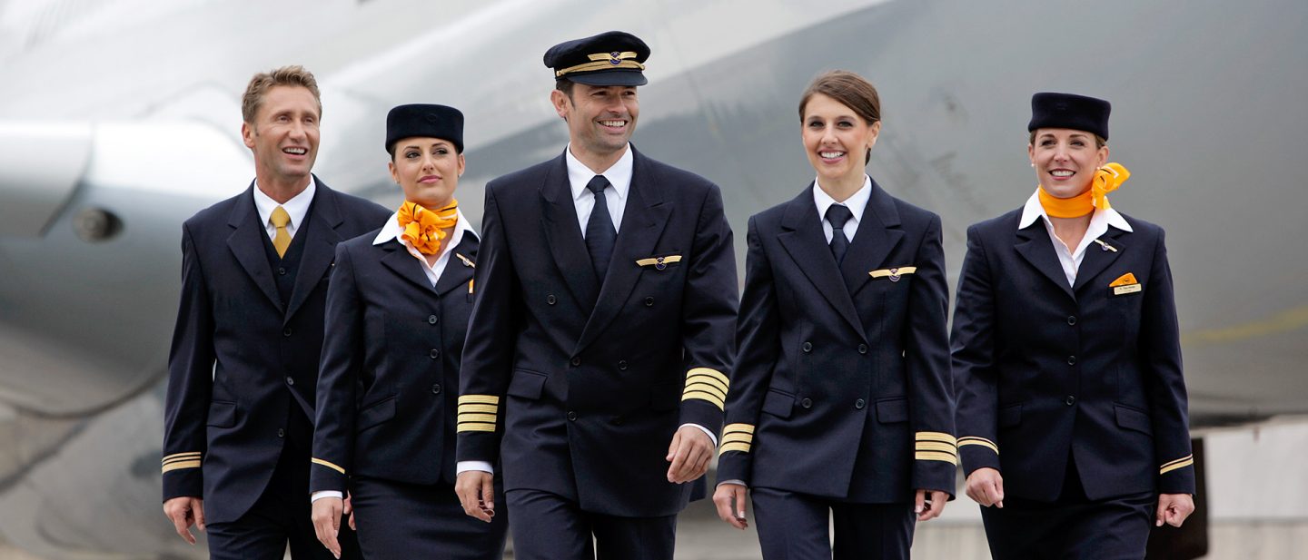 Pilot and cabin crew walk together on the tarmac in front of an aircraft.
