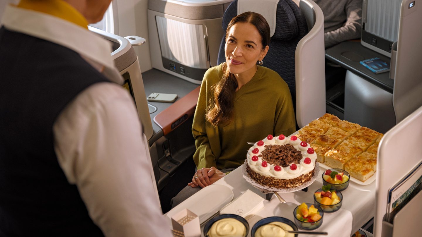 Woman in business class is served cake and pastries.