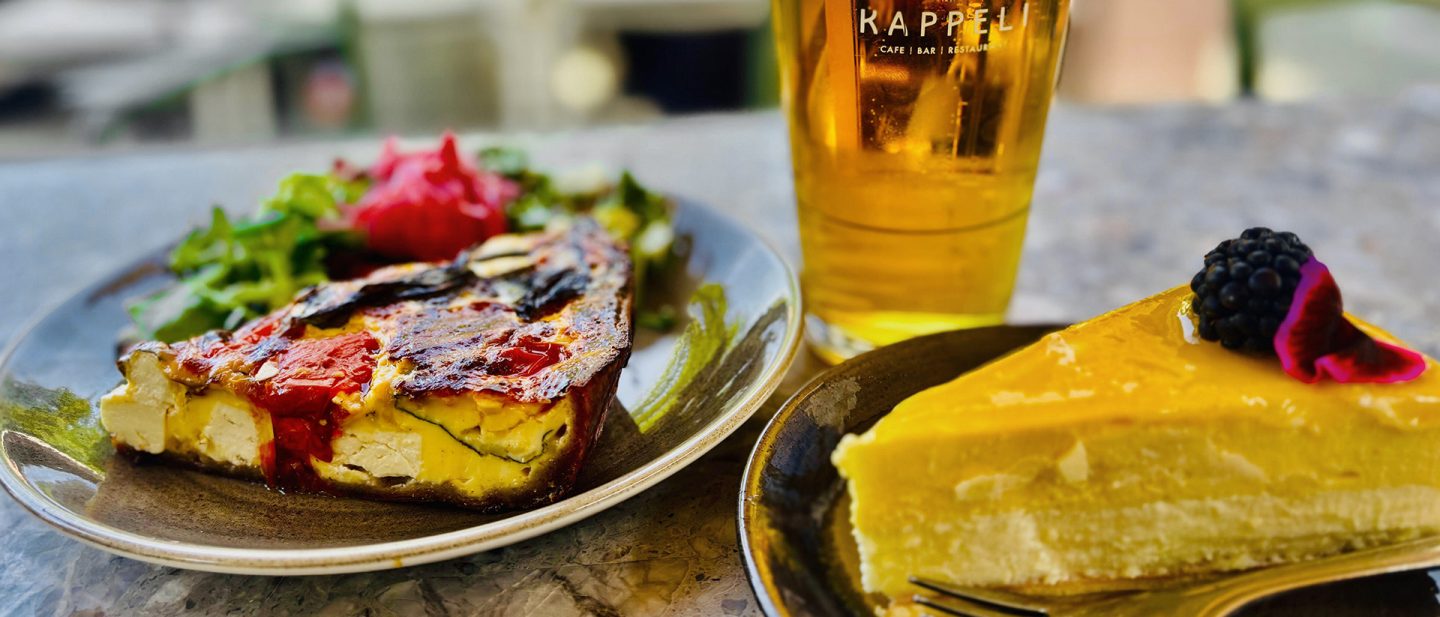 Roasted vegetable quiche and mango cheesecake served with a glass of beer.