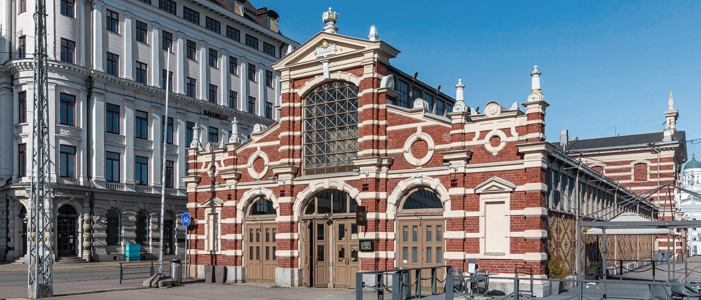 Historic red and white brick building with intricate facades and arched entrances under a clear sky.