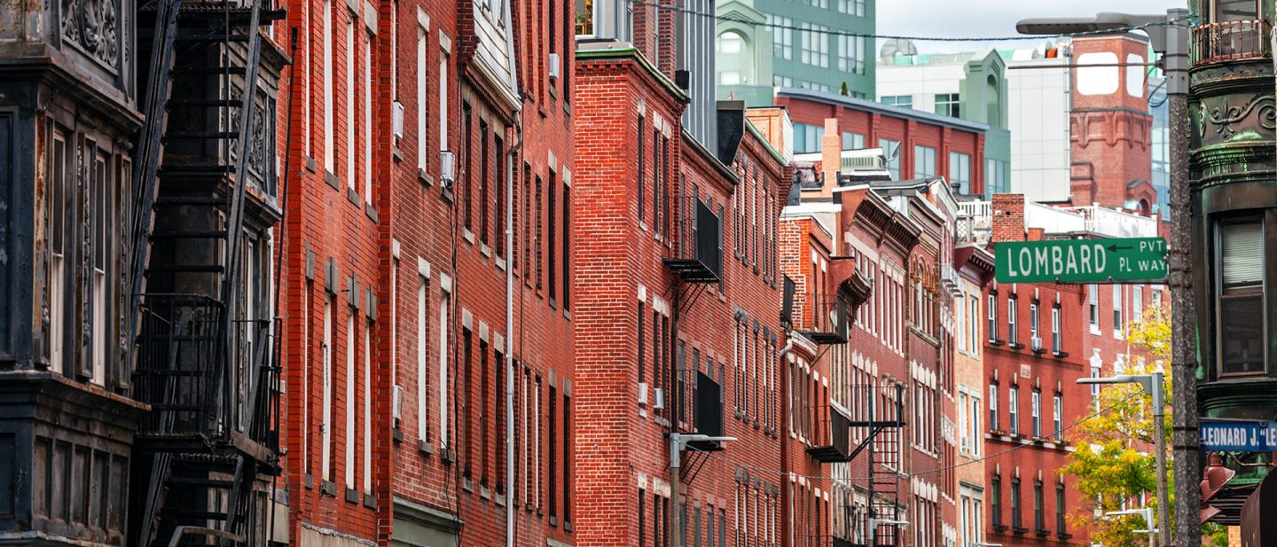 A street scene featuring historic red brick buildings and a street sign for “Lombard Pl Way.” 