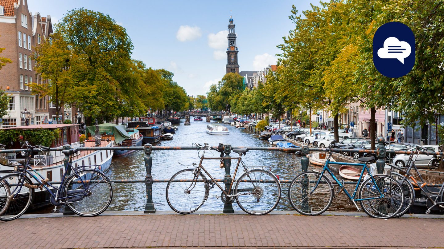 Team Stories: View of a canal in Amsterdam, with bicycles leaning against a bridge railing in the foreground.