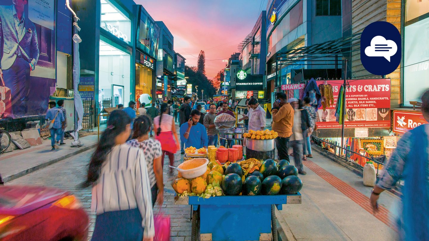 Team Stories: View of a street in Bengaluru at dusk with street vendors.