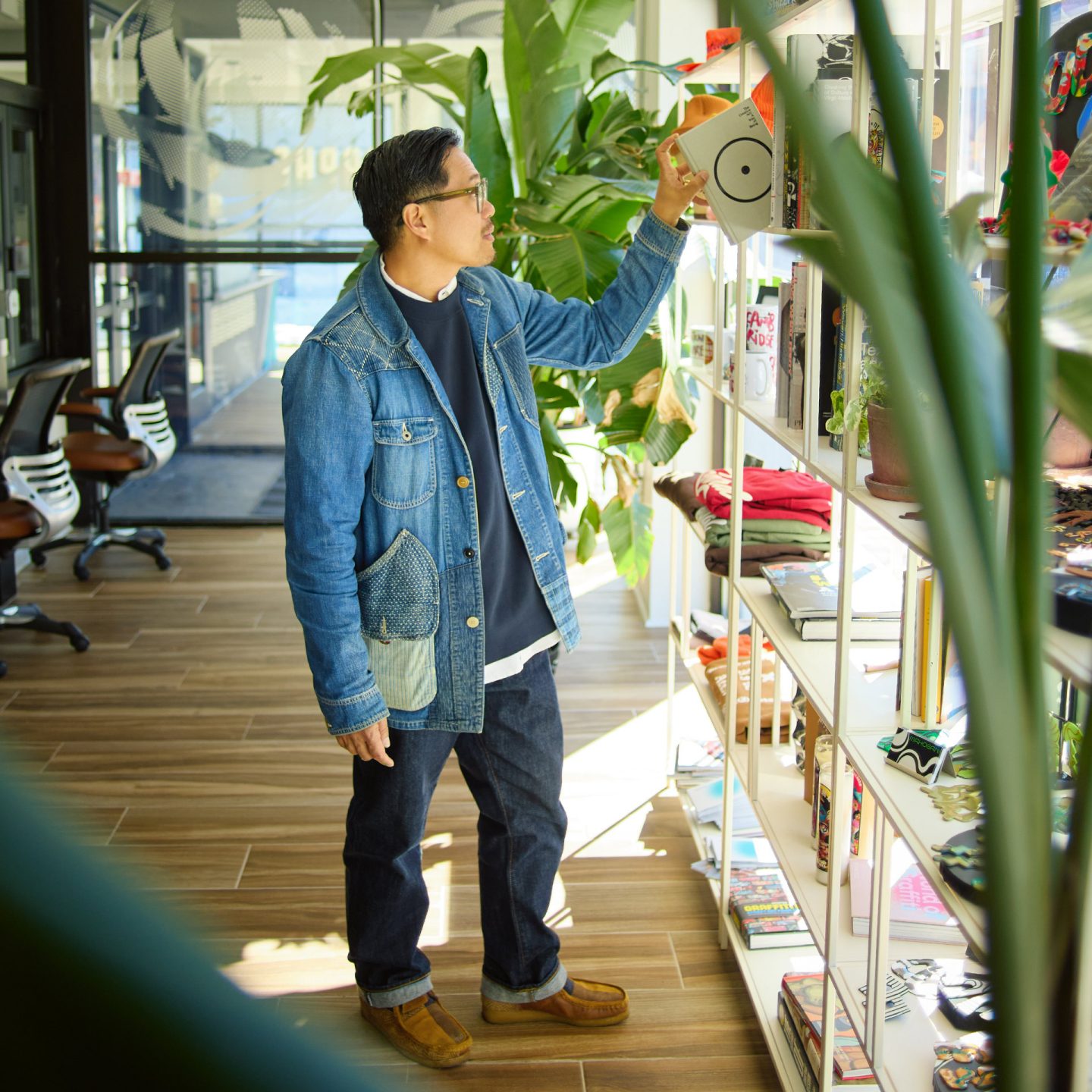 Oliver Mak stands in a brightly lit store, pulling a book from a shelf